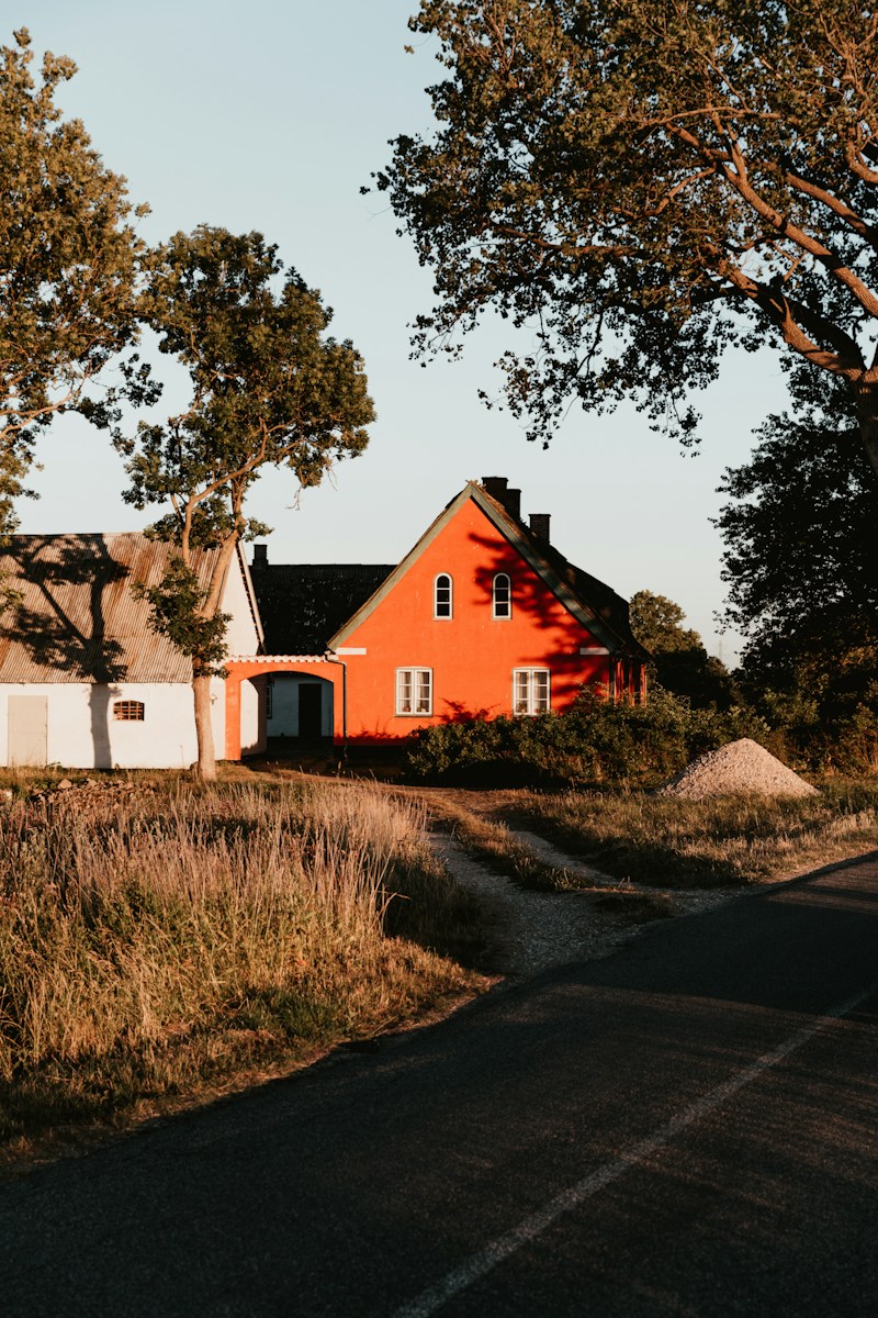 orange house with black roof beside white house with brown roof